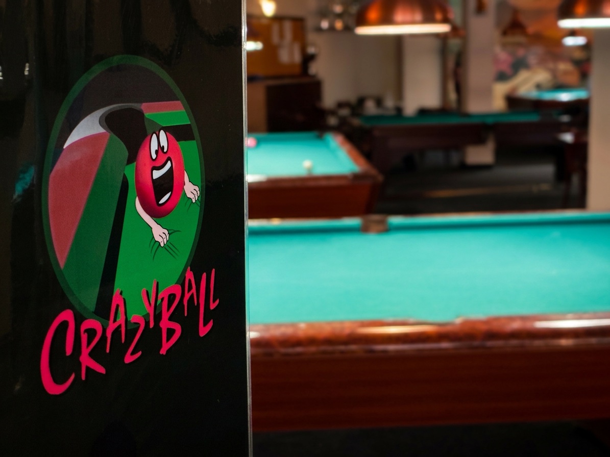 Crazyball logo on a pillar with pool tables behind
